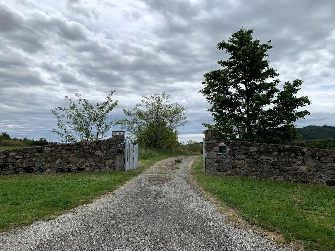 Le chemin d’accès à l’écurie, entre deux murs de pierre sèche et des arbres.