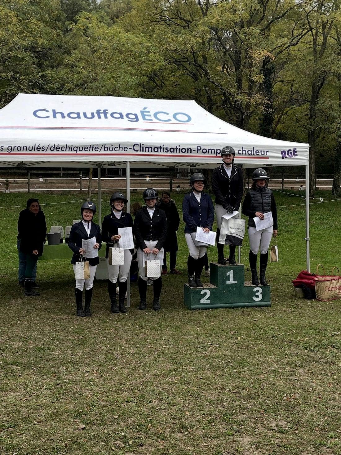 Remise des prix d’un concours de dressage, cavaliers alignés devant le podium.